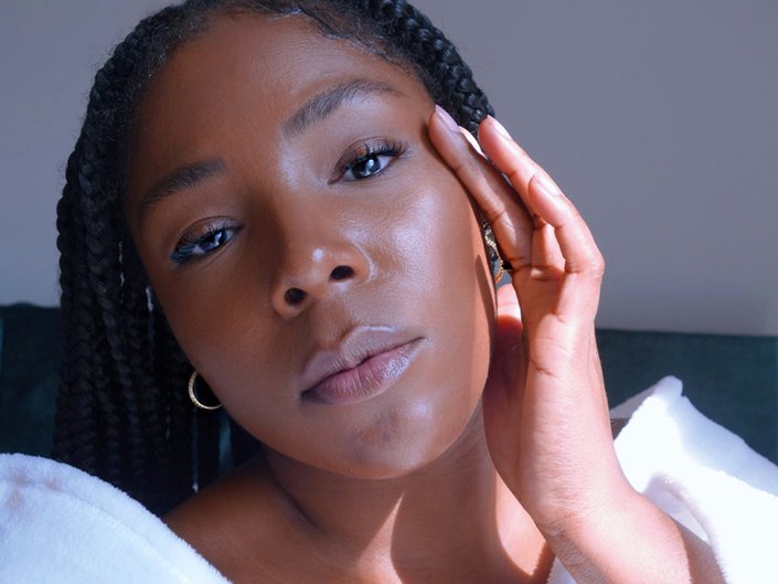 Image of black model tilting her head to the side and touching the left side of her face