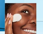 A woman rubbing a lotion into her face