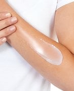 Close-up of a hand applying a soothing salve to cracked skin, illustrating the use of different skin treatment products.