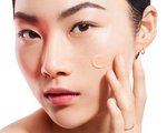 Photo of a woman and applying moisturizer to her cheek